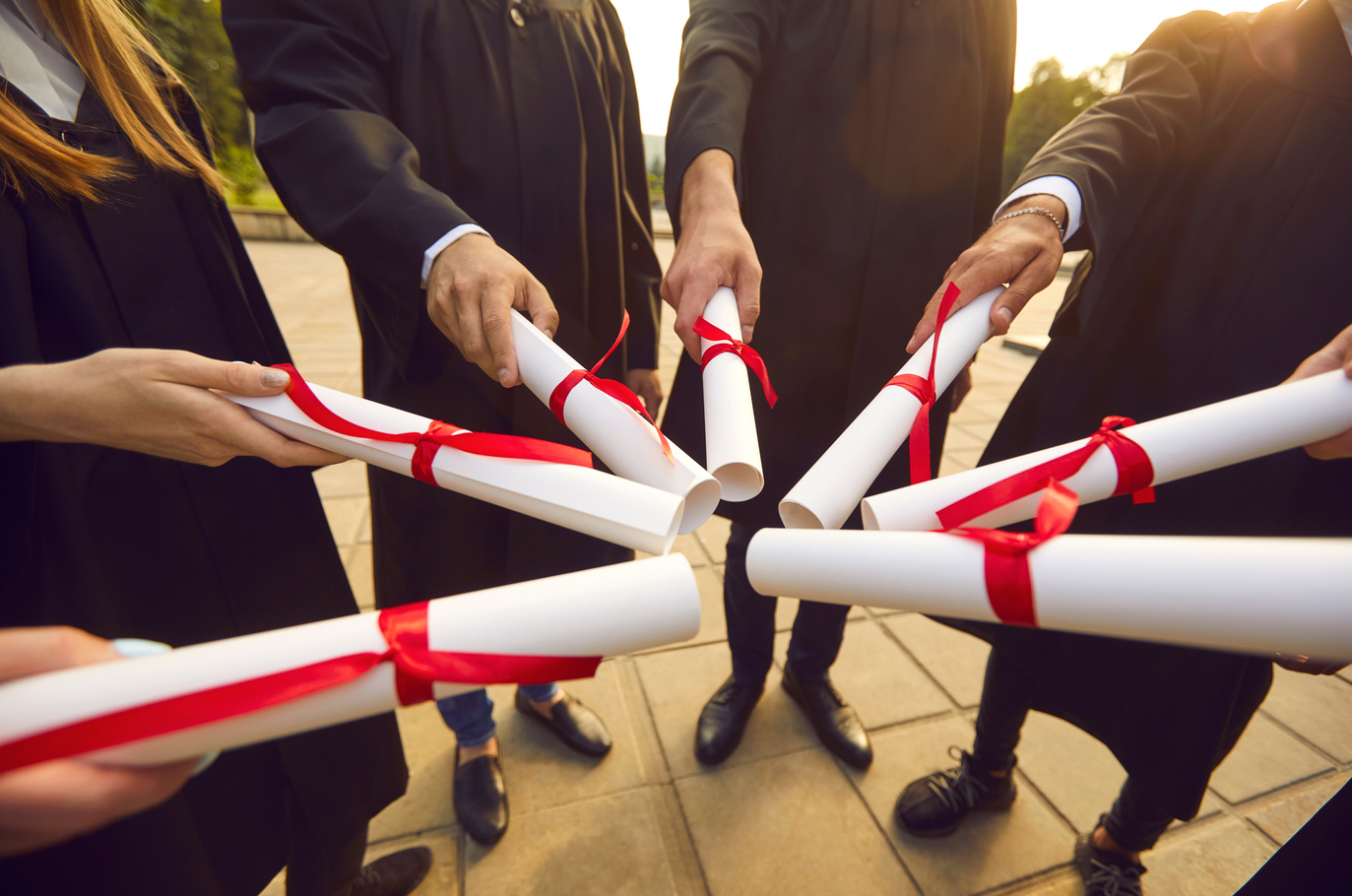 University or College Graduates Join Diplomas Standing in Circle at Graduation Party